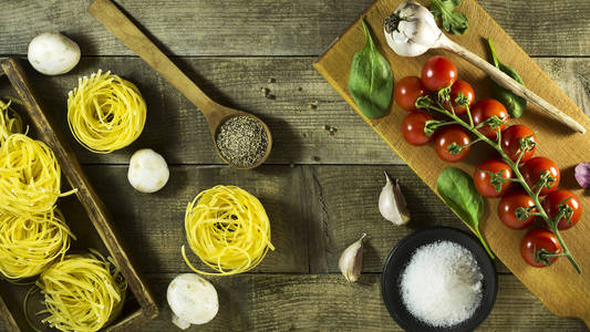 意大利面食 樱桃西红柿 大蒜 蘑菇和香料仿古木制的桌子上