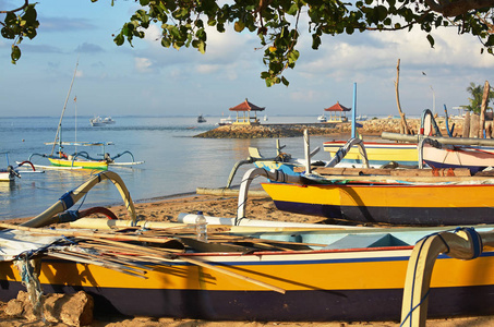 巴厘岛支腿渔船和设备在黎明时分在沙努尔海滩上休息