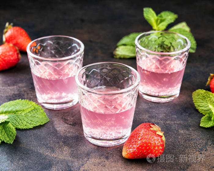 自制的草莓甜酒在金属桌上酒杯中的酒精水果鸡尾酒镜头