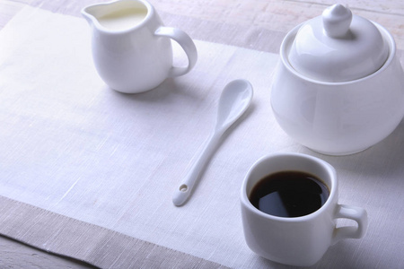 一杯热咖啡, 咖啡豆, 牛奶壶, 白色背景的糖碗, 复印空间。咖啡概念