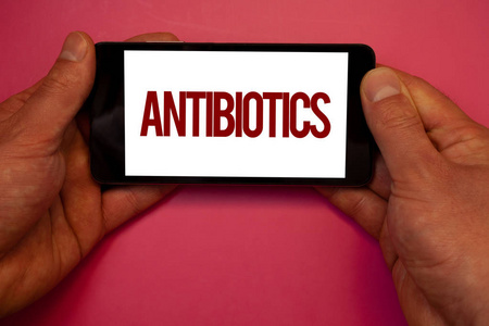 概念性手写显示抗生素。商业照片展示药物用于治疗和预防细菌 infectionsman 持有手机白屏黑红色字母
