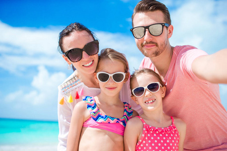 年轻漂亮的家庭以自拍照在沙滩上