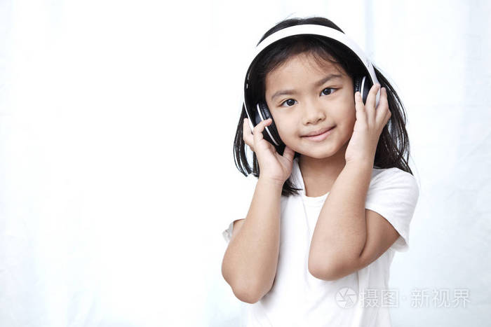 可爱的小女孩与智能手机和耳机听音乐和舞蹈