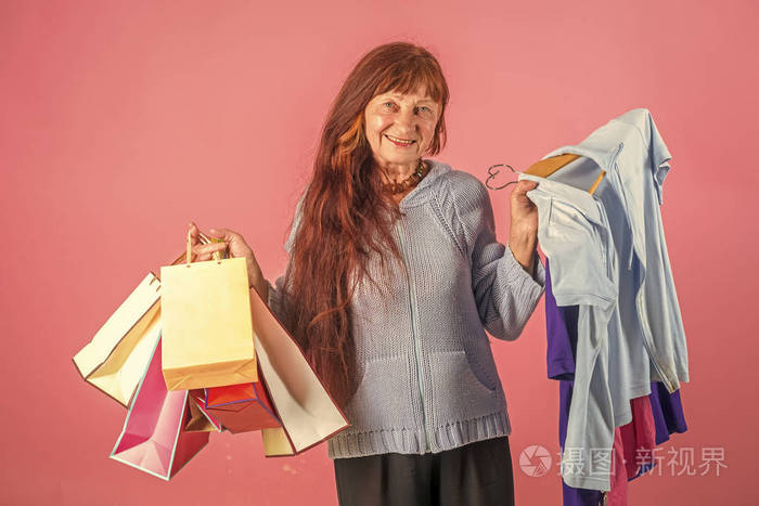 女人用长红的头发抱着五颜六色的购物袋。圣诞节和生日。快乐女人手里的衣服