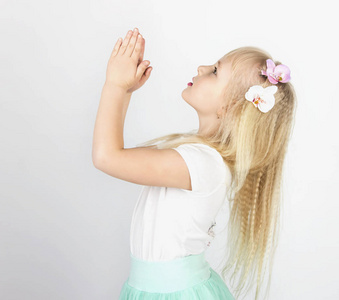 金发碧眼的小女孩双手合十祈祷上帝一个小天使侧面视图照片