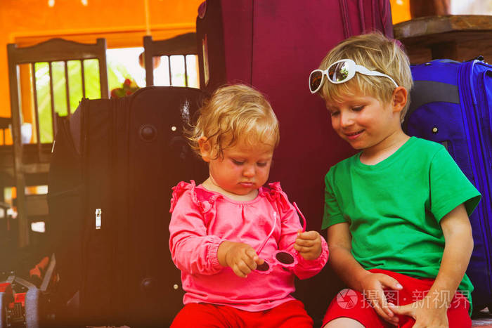 小男孩和蹒跚学步的女孩坐在行李箱准备旅行