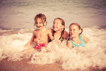 三个快乐的孩子们在沙滩上玩