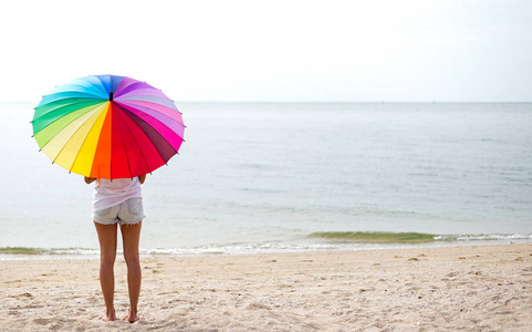 在海滩上跳跃着伞和快乐的年轻妇女。旅游和度假。自由概念