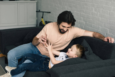 家庭沙发上的快乐父亲和小儿子肖像