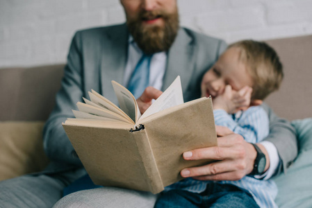 选择焦点的商人和小儿子一起看书沙发在家里, 工作和生活平衡