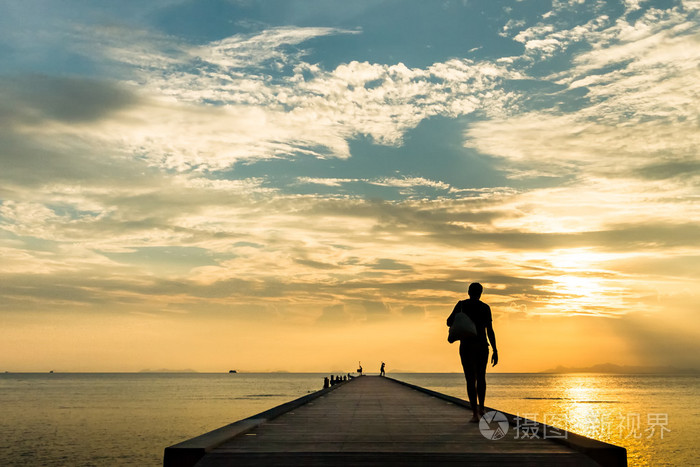 在码头上走在日落时分在一个热带小岛上的女人。苏梅岛，泰国