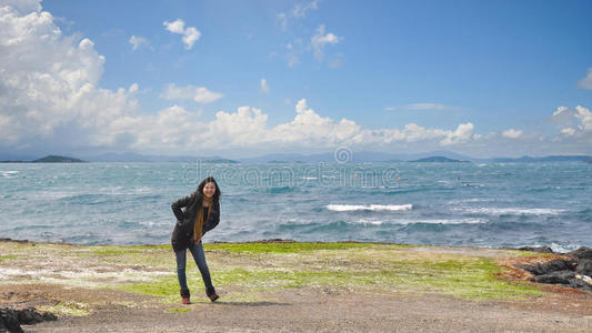 美丽的年轻女孩站在海洋前