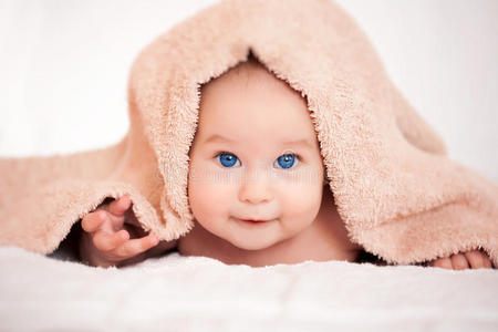 婴儿躲在米色毛巾下面
