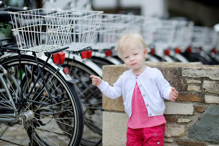 可爱的女孩站在一排自行车旁