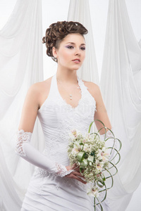 一位年轻的黑发新娘，穿着白衣服，手持鲜花
