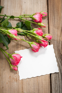 粉色玫瑰和白色卡片，在木制ta上有一个文本位置