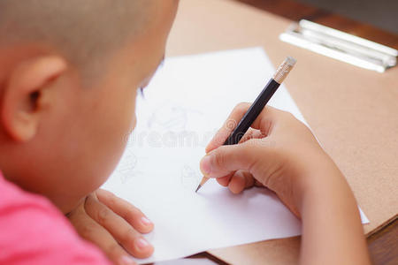 一个亚洲男孩在白纸上写字