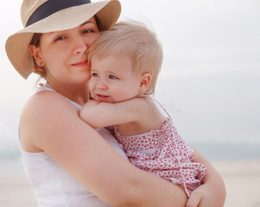 母亲抱着海湾女孩在海滩上的画像