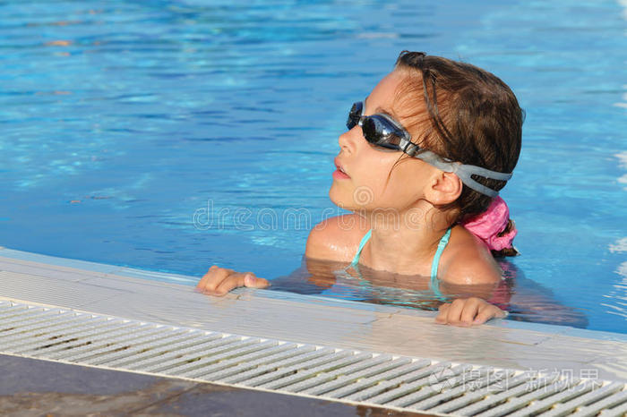 可爱的女孩戴着护目镜在游泳池游泳