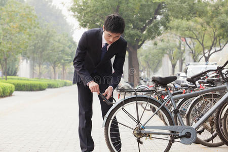 北京一个年轻的商人把自行车锁在城市街道上