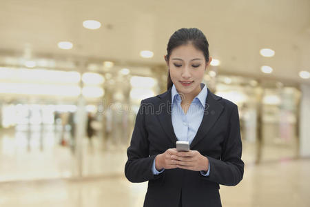 年轻女商人在室内用手机发短信