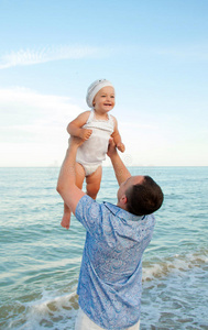 年轻的父亲和他的女儿在海滩上。