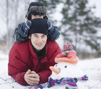 快乐的父亲和儿子在外面和雪人在一起