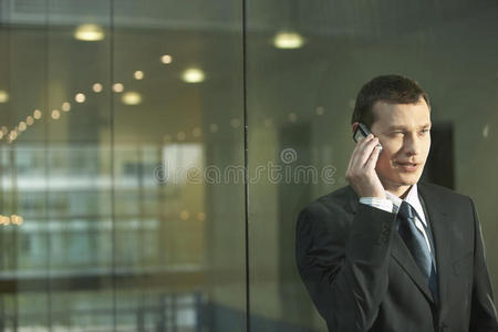 站在玻璃墙上用手机的商人