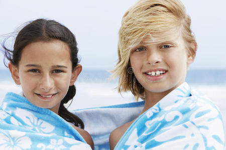 快乐的男孩和女孩在沙滩上裹着毛巾