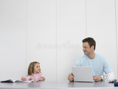 爸爸和女儿画画和使用笔记本电脑