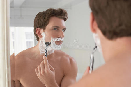 浴室镜子里刮胡子的男人