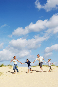 一家人手牵手在沙滩上奔跑