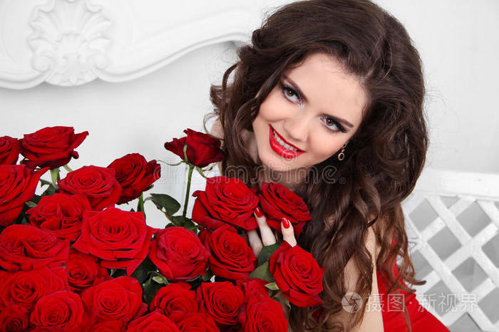 卖弄风情的女孩。情人节这天，美丽幸福的女人带着一束红玫瑰花在室内的公寓里。