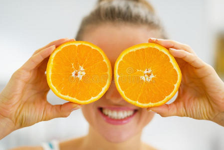 快乐的年轻女子拿着两片橘子
