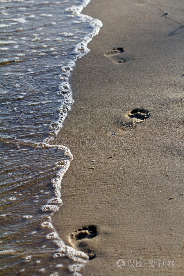 傍晚温暖的沙滩上的脚印