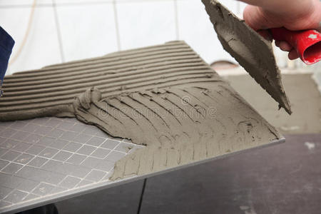 瓷砖胶铺贴建筑工人正在家里贴瓷砖地板胶照片