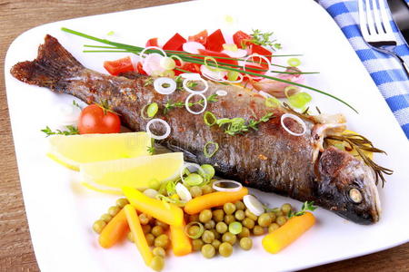 烤鳟鱼配不同的蔬菜和餐具