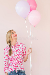 女人抬头看着粉色背景下的气球