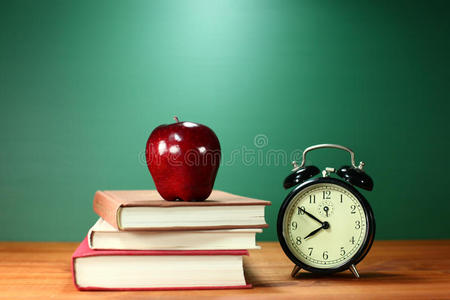 学校书桌上的书苹果和钟