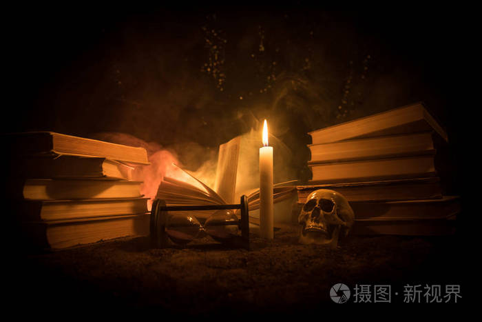 向导的办公桌由烛光照亮的桌子人类的头骨沙子表面上的旧书万圣节静物