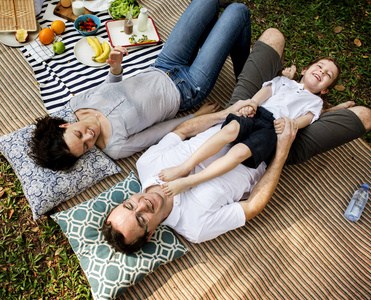 野餐时躺在毯子上的一家人图片