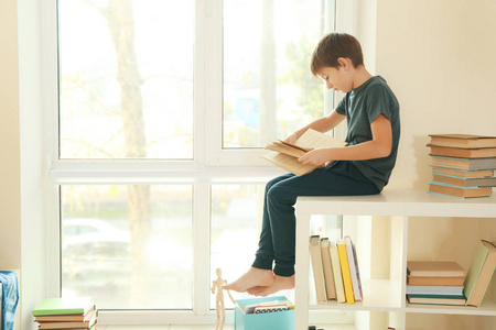可爱的小学生坐在窗边看书