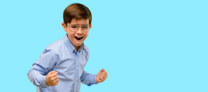 英俊的蹒跚学步的孩子带着绿色的眼睛快乐而兴奋地庆祝胜利, 表达了