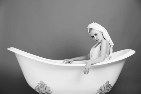 女性时尚的概念。漂亮的女人, 毛巾头巾坐在白色浴缸