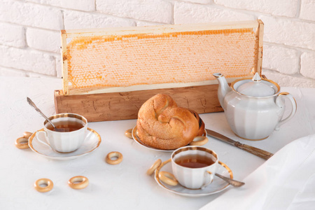 杯茶和茶壶配蜂蜜和甜包子在白砖背景