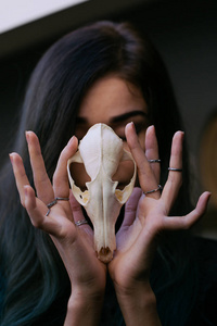 一个年轻的女孩，一只狐狸的手里拿着一个神秘的头骨的画像。画长长的头发