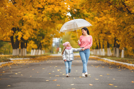 年轻漂亮的母亲与她的小女儿在秋季背景的乐趣。秋天快乐的家庭