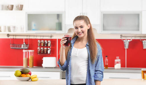 年轻美丽的女人在厨房喝果汁图片