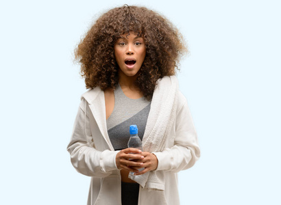 非洲裔美国人健身妇女拿着水瓶子吓坏了惊讶的脸, 害怕和兴奋与恐惧的表情