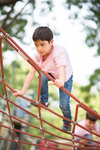 小男孩爬上绳子在操场上